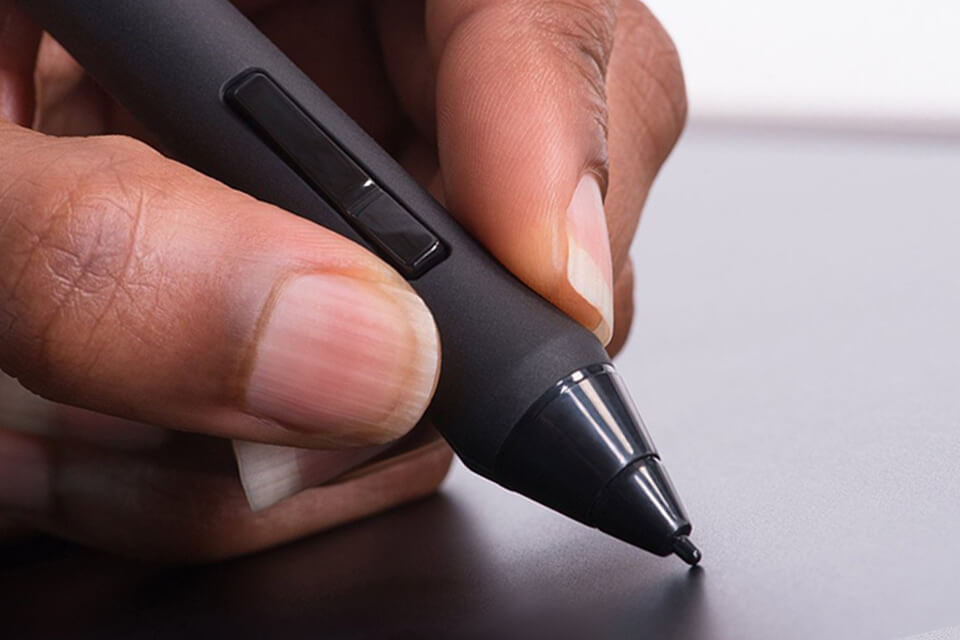 A close-up image of a person holding a black stylus pen with different features and brands.