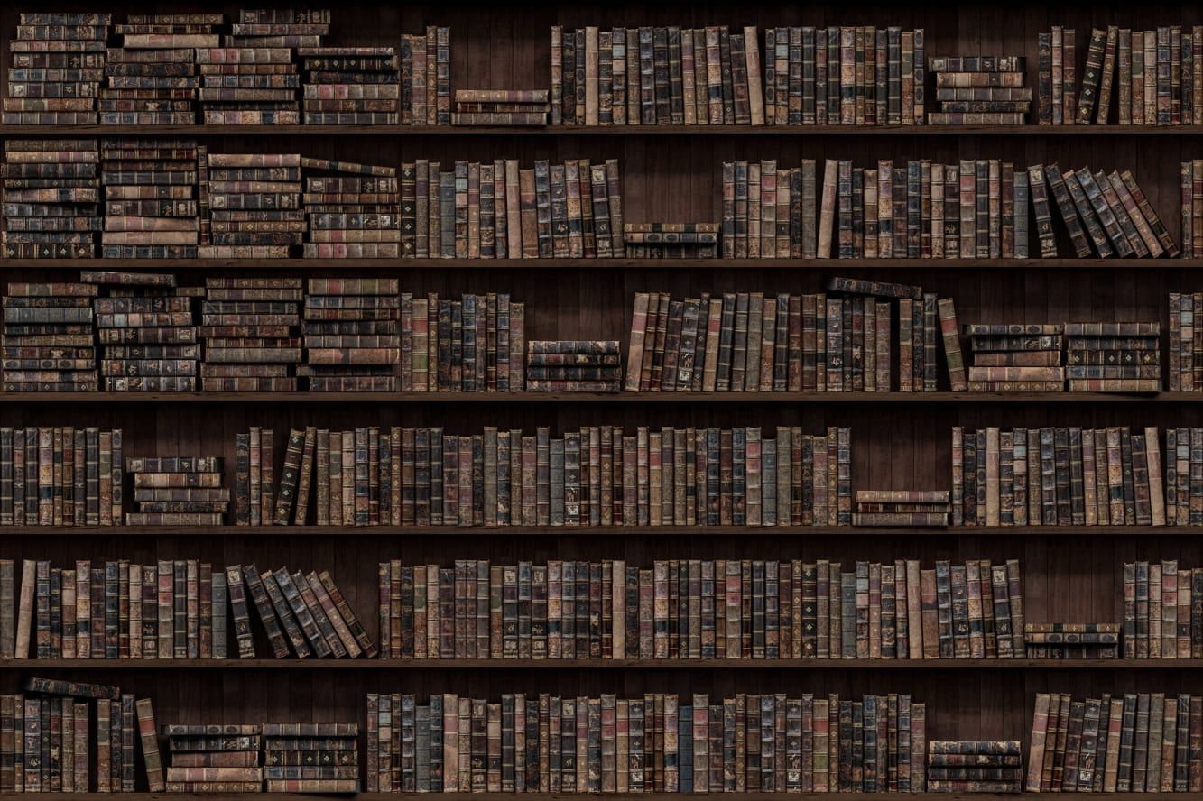 An image of several bookshelves filled with a variety of books, including old, leather-bound books, newer hardcovers, and paperbacks.