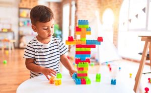 A toddler is playing with colorful building blocks on a soft play mat.