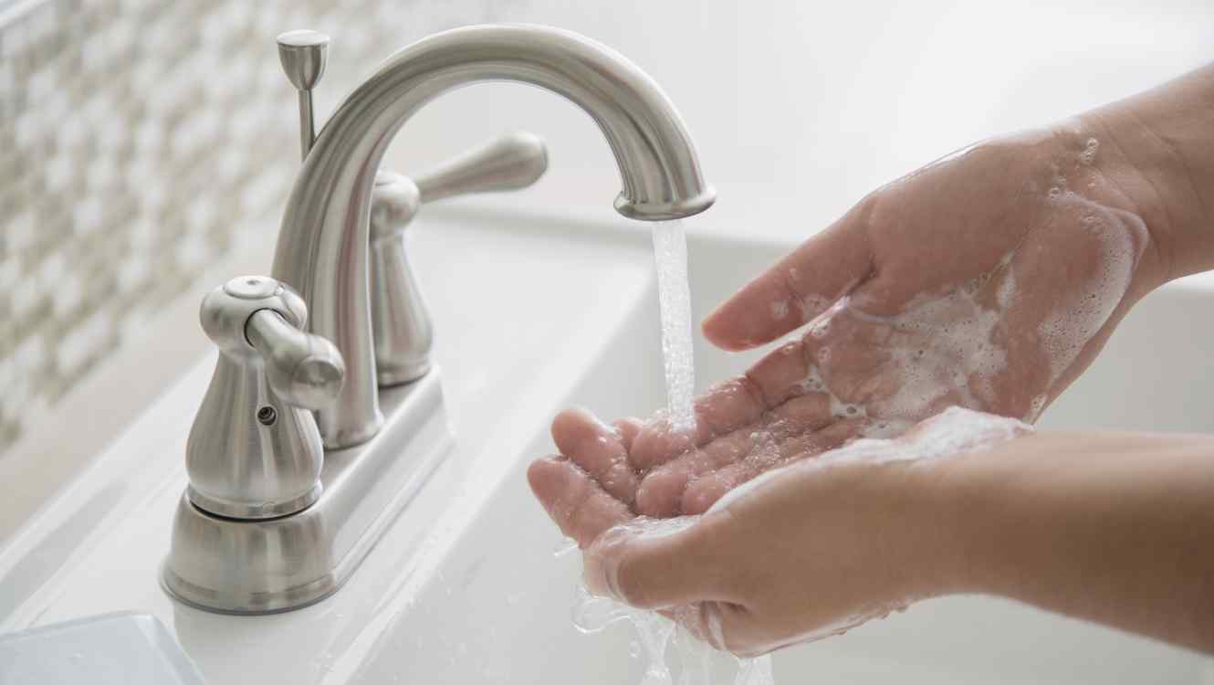 A person thoroughly washing their hands with soap and water to prevent the spread of germs.