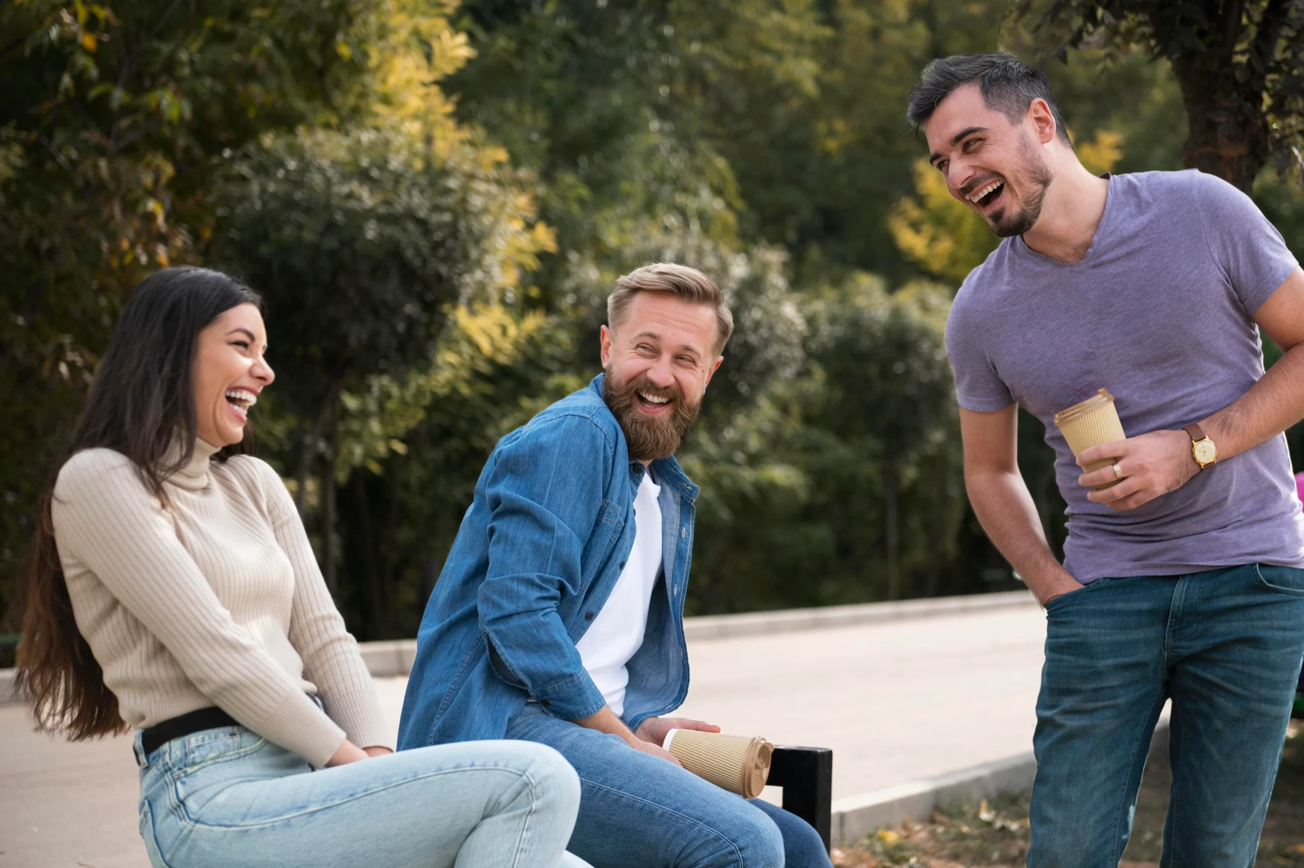 Three friends are laughing and enjoying each other's company in a park, which improves overall health by reducing stress, boosting mood, and strengthening social bonds.