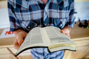 A man is reading a book while sitting in a comfortable chair.