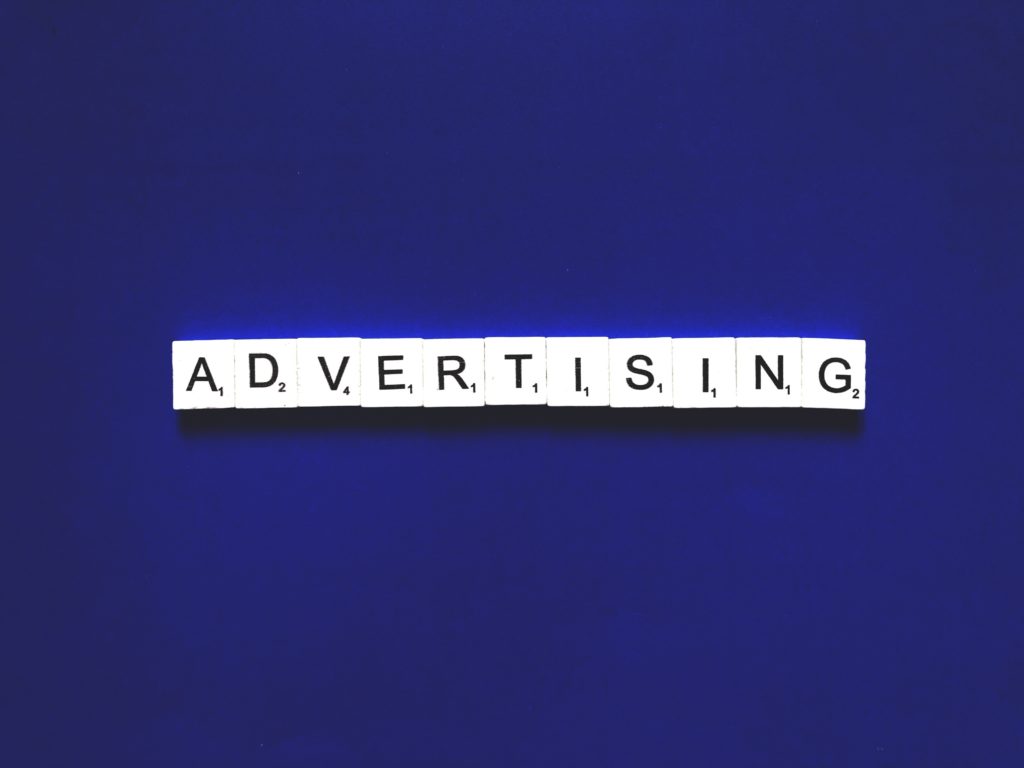 A blue background with white tiles spelling out 'ADVERTISING'. The image represents the search query 'Apps that make money without inviting friends'.