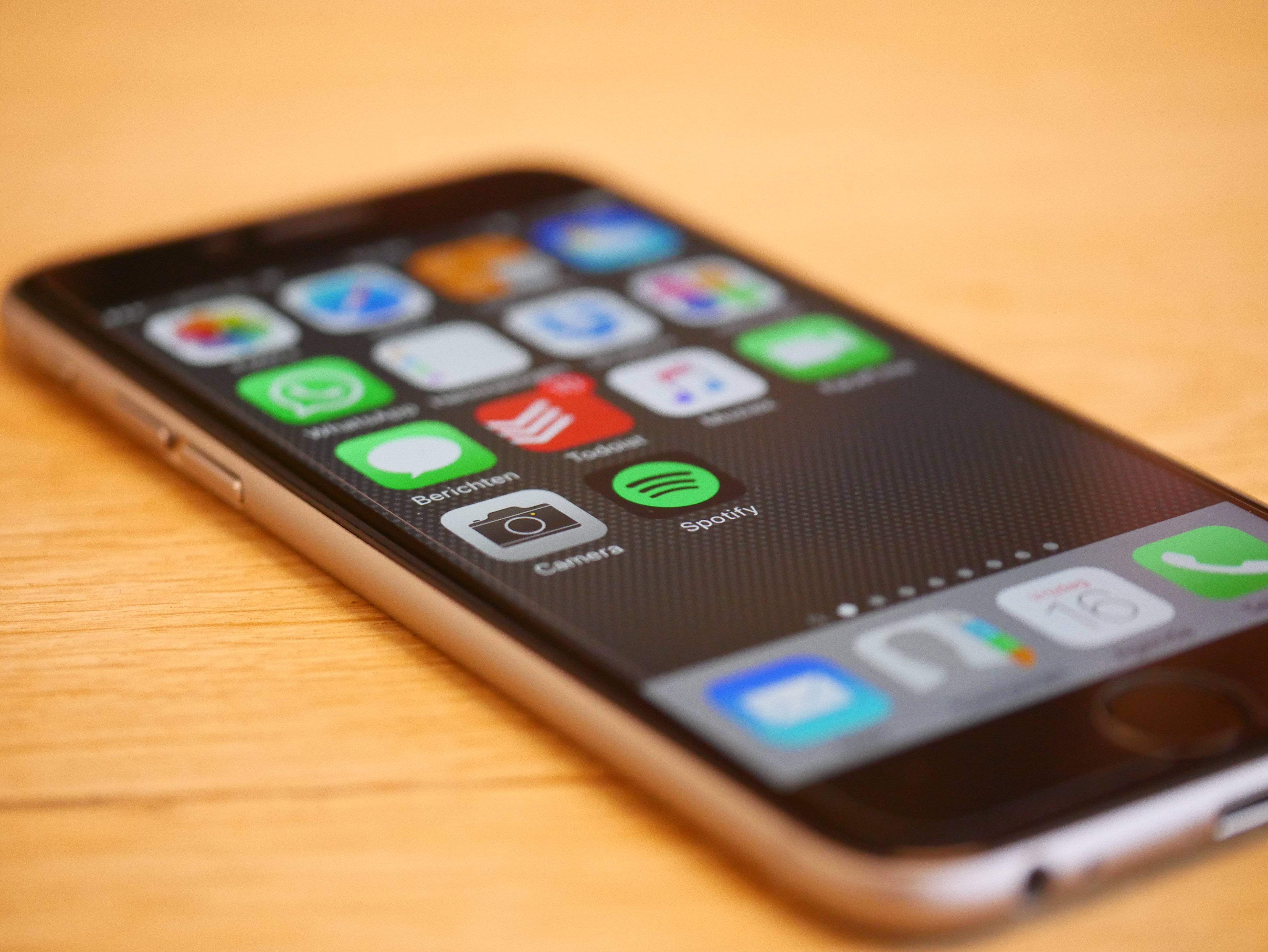 A smartphone with a message on the screen that says "Device incompatibility" sits on a wooden table.