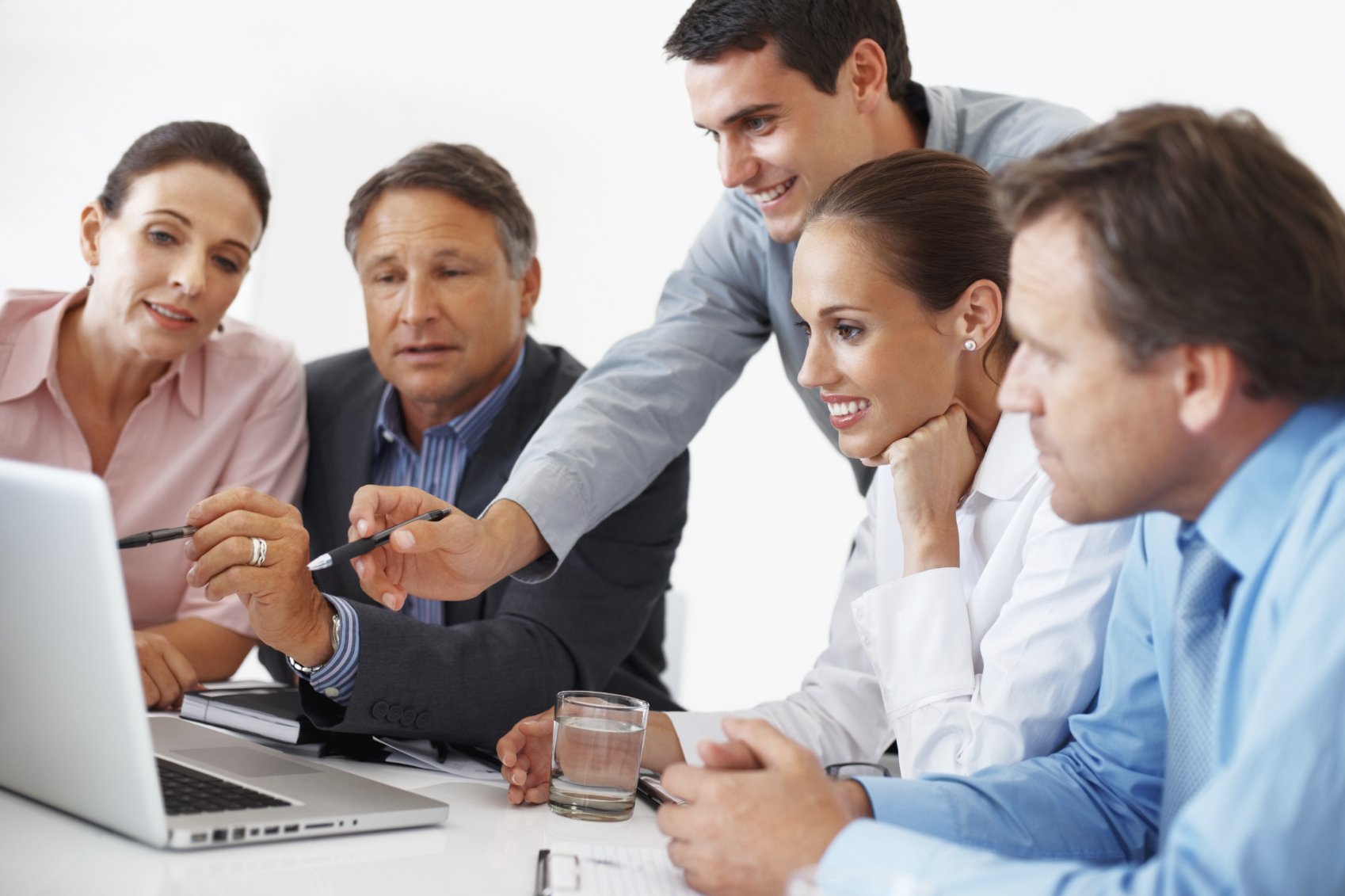 A group of people are working together in an office. They are looking at a laptop and smiling. They are brainstorming ideas and working together to overcome procrastination.