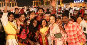 People from different cultures wearing traditional clothing are celebrating together at a festival.