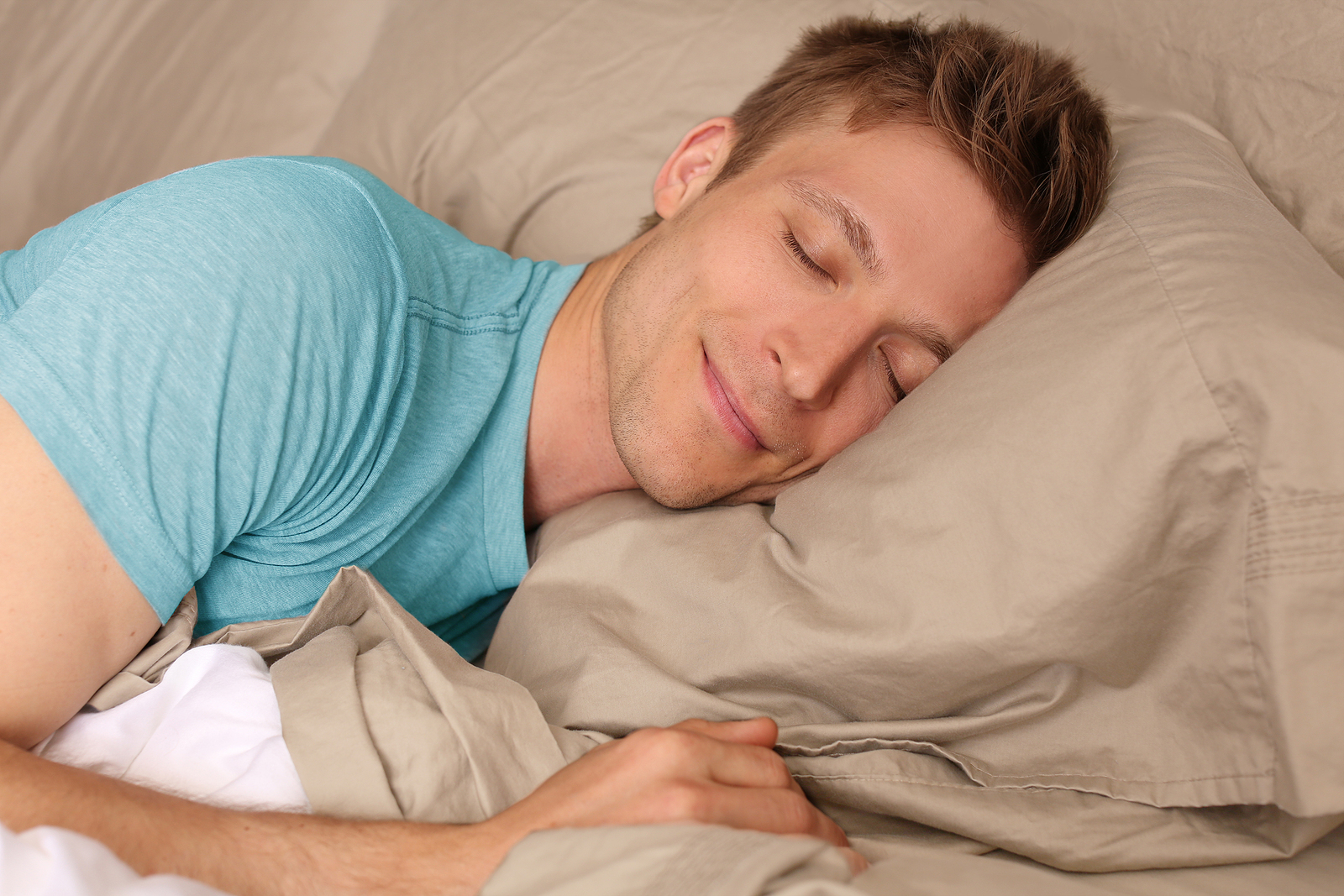 A young man is sleeping soundly with a smile on his face.