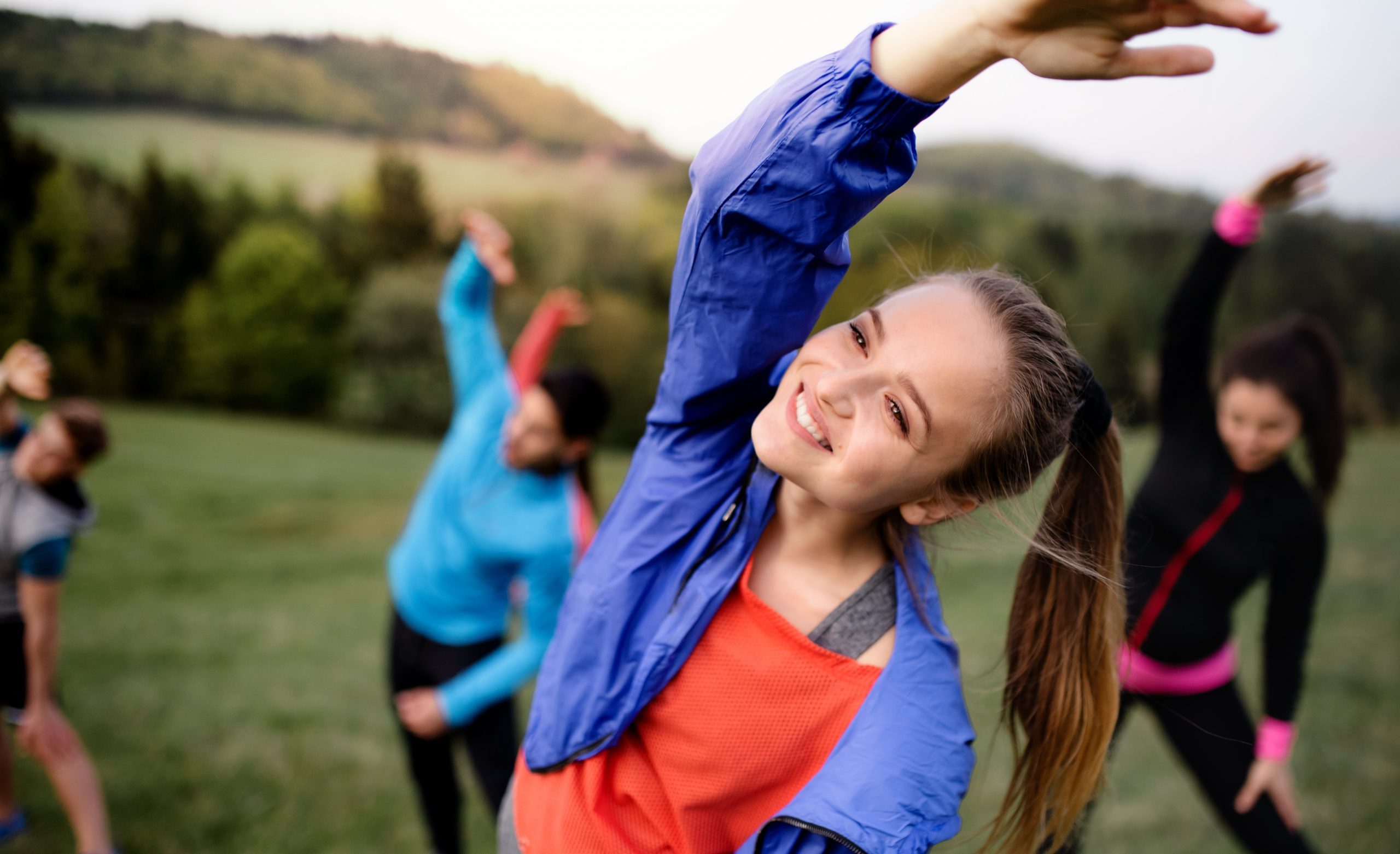 A group of people doing stretching exercises outdoors.