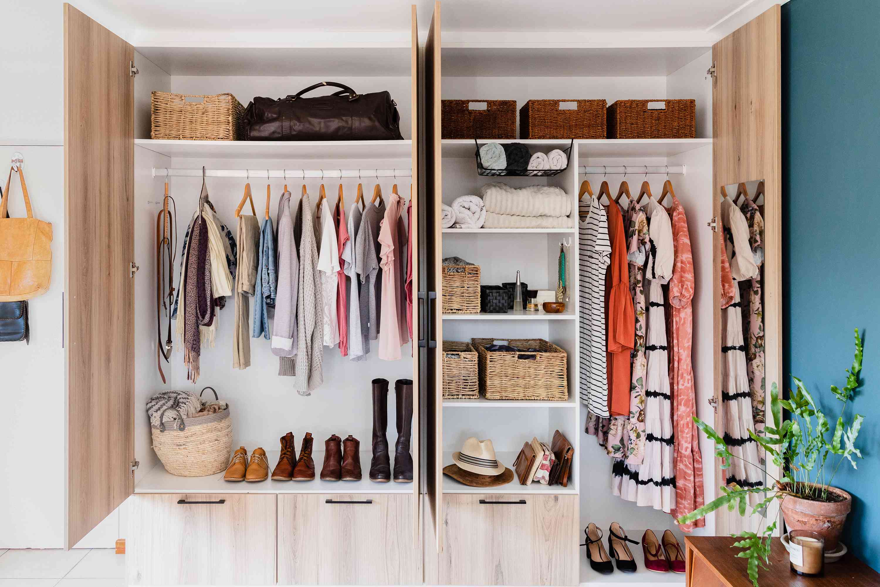 An organized closet with clothes hanging on racks and folded on shelves, as well as shoes, bags, and accessories neatly arranged in baskets and cubbies.