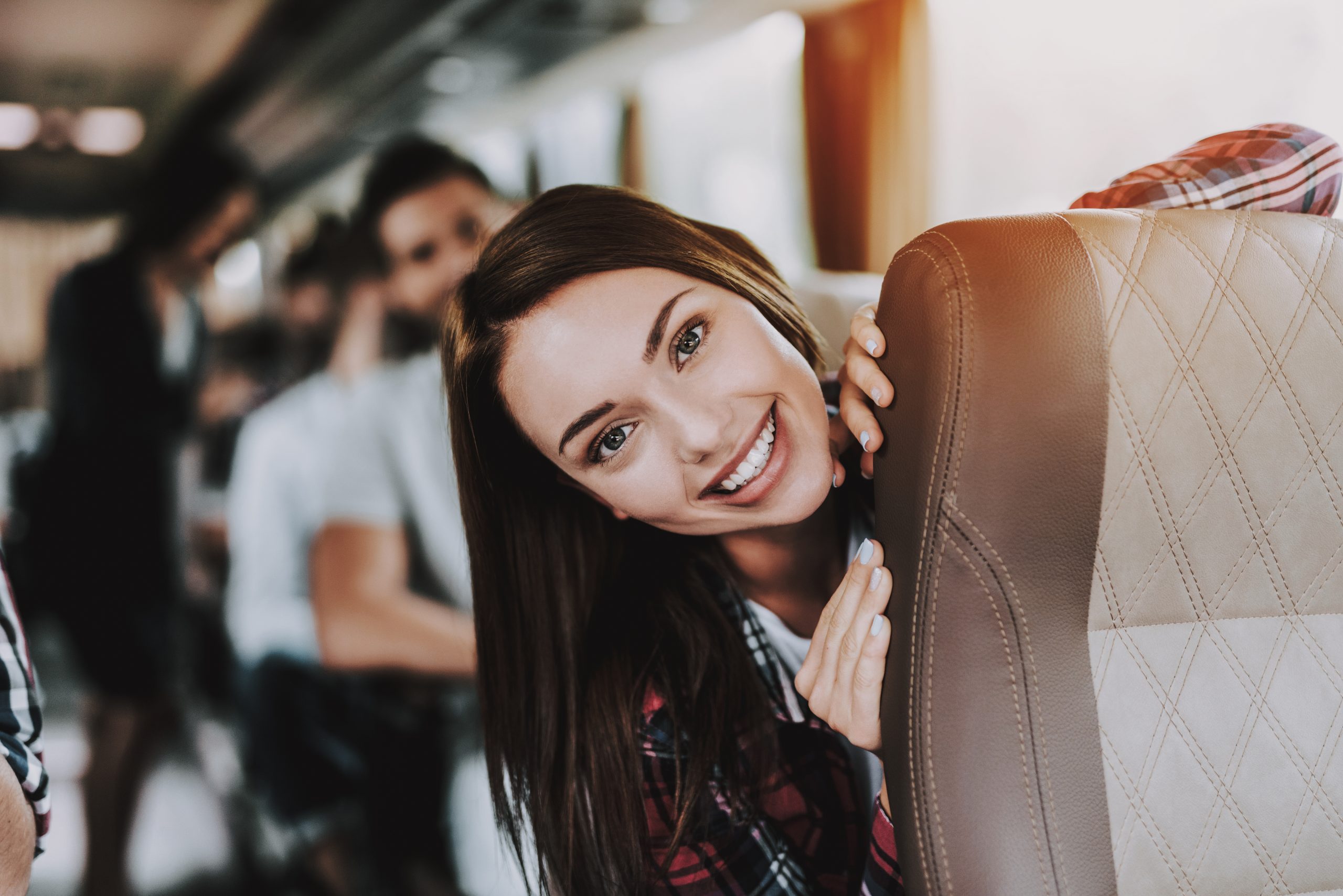 A young woman smiles while traveling by bus with friends.