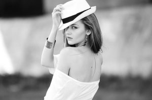 A black and white photo of a woman wearing a white hat and white shirt looking over her shoulder, with the text 'Red flags in online dating' superimposed on the right side of the photo.