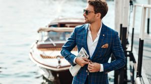 A man in a suit standing on a dock next to a boat, with the option to edit the photo.